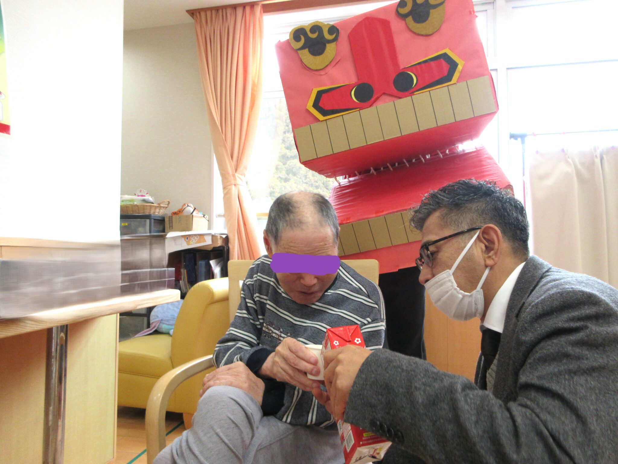 入居者とスタッフがレクリエーション活動で一緒に遊んでいる風景。季節装飾が施された共用スペース。